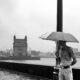 A person standing on a bridge with an umbrella